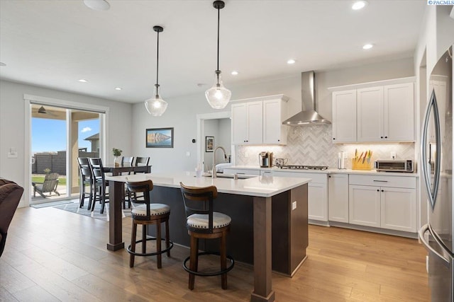 5770 W 40th Ave, Kennewick, WA 99338 - kitchen featuring wall chimney range hood, backsplash, appliances with stainless steel finishes, white cabinetry, and an island with sink