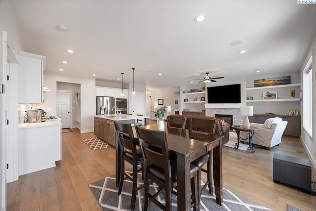 5770 W 40th Ave, Kennewick, WA 99338 - dining space with ceiling fan, a warm lit fireplace, light wood-style flooring, and recessed lighting