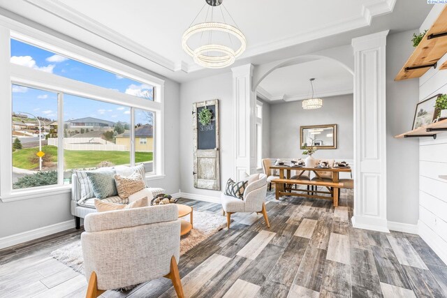 interior space with decorative columns, crown molding, wood finished floors, and arched walkways