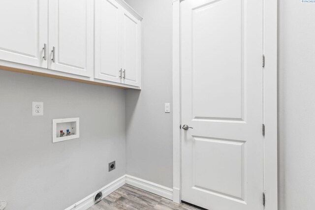 clothes washing area with hookup for an electric dryer, light wood-type flooring, hookup for a washing machine, baseboards, and cabinet space