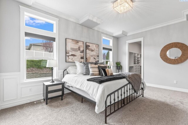 carpeted bedroom featuring a wainscoted wall, ornamental molding, and a decorative wall