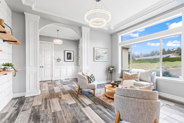 sitting room with a wealth of natural light, an inviting chandelier, and decorative columns