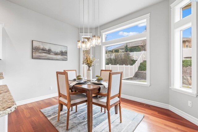 dining space featuring visible vents, baseboards, a chandelier, and wood finished floors