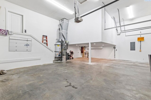 garage featuring strapped water heater, a garage door opener, and electric panel
