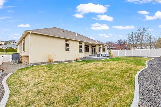 back of property with a gate, a fenced backyard, a lawn, stucco siding, and a patio area