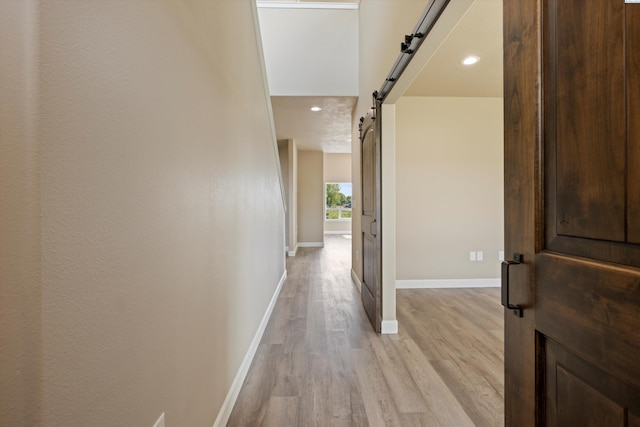 hall with a barn door and light wood-type flooring