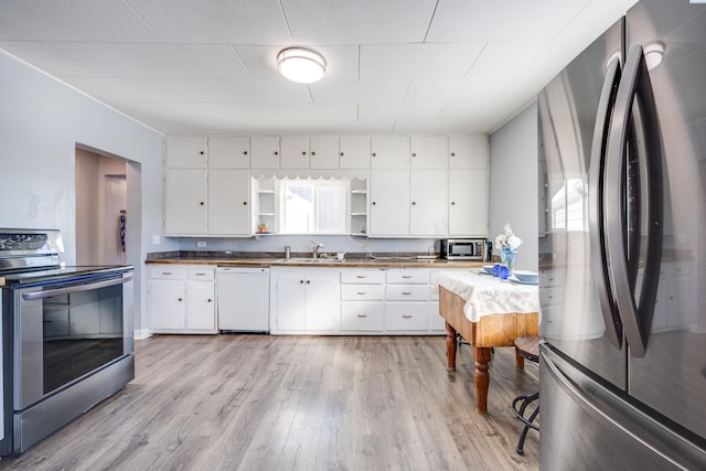 kitchen featuring fridge, stainless steel range with electric stovetop, white dishwasher, and white cabinets