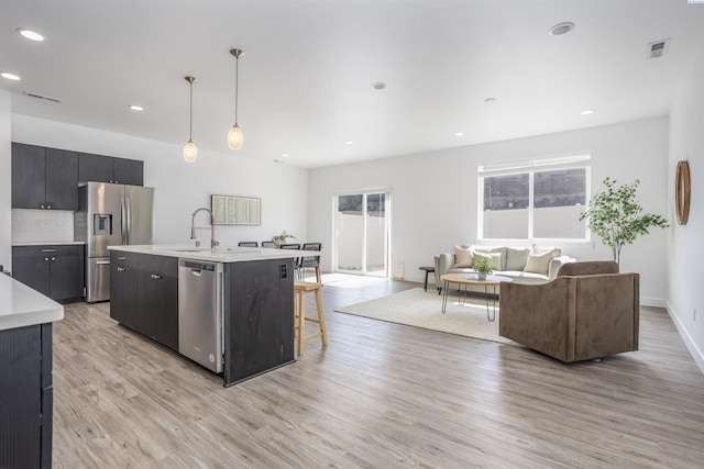 kitchen featuring stainless steel appliances, a wealth of natural light, light wood finished floors, and light countertops