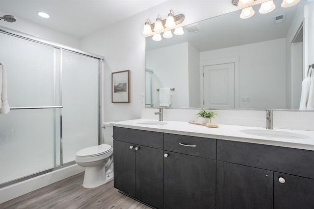 bathroom with double vanity, visible vents, a sink, and wood finished floors
