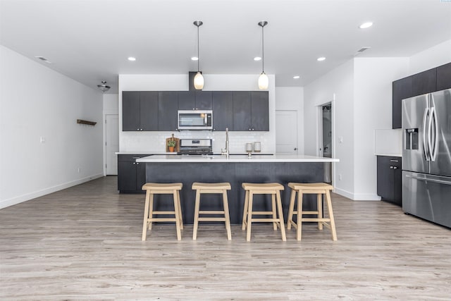 kitchen with light countertops, a kitchen breakfast bar, baseboards, and stainless steel appliances