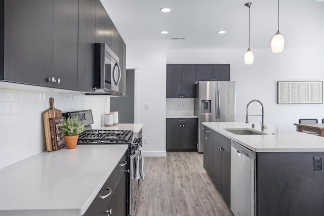 kitchen featuring tasteful backsplash, a sink, light countertops, light wood-style floors, and stainless steel appliances