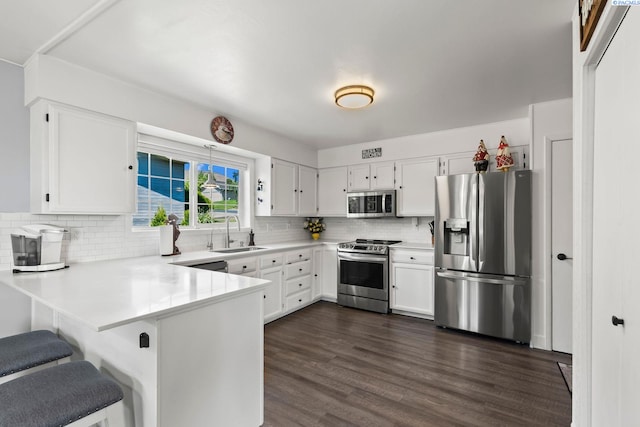 602 N 57th St, Yakima, WA 98901 - kitchen featuring appliances with stainless steel finishes, a peninsula, tasteful backsplash, light countertops, and dark wood-style floors