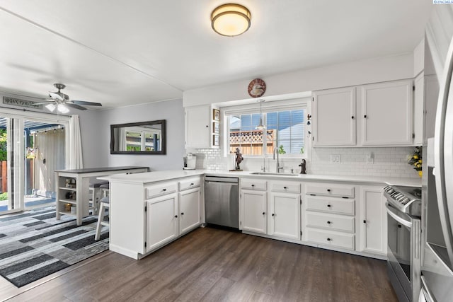 602 N 57th St, Yakima, WA 98901 - kitchen featuring appliances with stainless steel finishes, a peninsula, dark wood-style floors, and white cabinetry