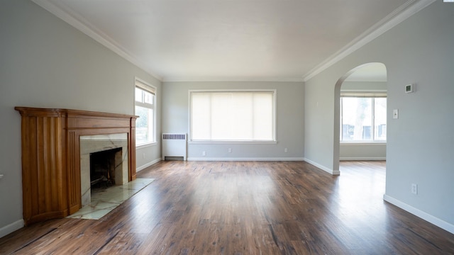 201 W Cooper St, Colfax, WA 99111 - unfurnished living room featuring radiator, arched walkways, wood finished floors, and crown molding