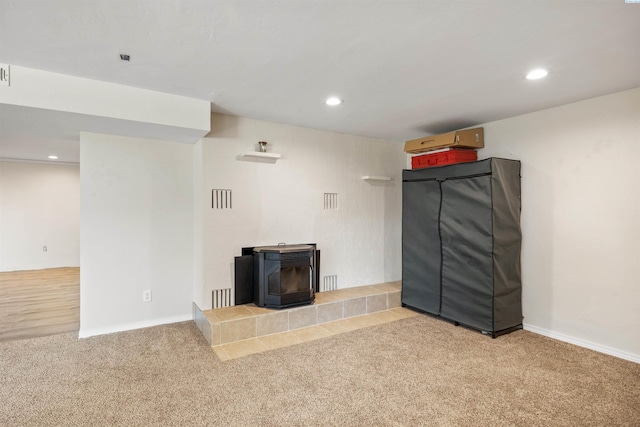 unfurnished living room featuring a wood stove and carpet flooring