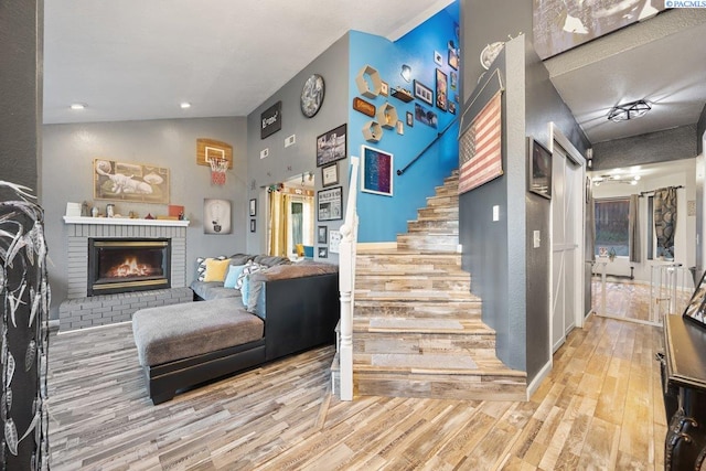 3715 Meadow Beauty Dr, Pasco, WA 99301 - living area featuring a brick fireplace, stairway, vaulted ceiling, and wood finished floors