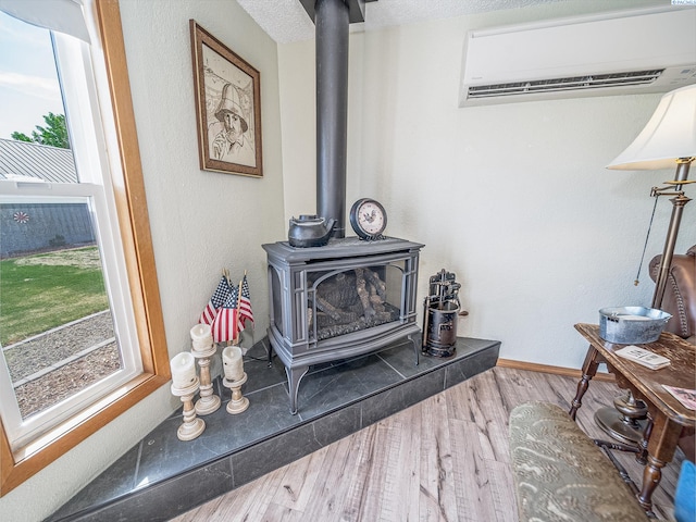3680 E Euclid Rd, Mabton, WA 98935 - detailed view of a wall mounted AC, a wood stove, wood finished floors, baseboards, and a textured wall