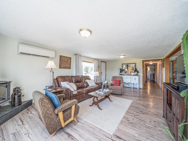 3680 E Euclid Rd, Mabton, WA 98935 - living room featuring an AC wall unit, a wood stove, a textured ceiling, and wood finished floors