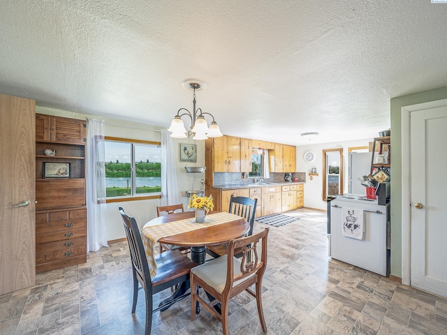 3680 E Euclid Rd, Mabton, WA 98935 - dining room featuring a chandelier, stone finish floors, a textured ceiling, and baseboards