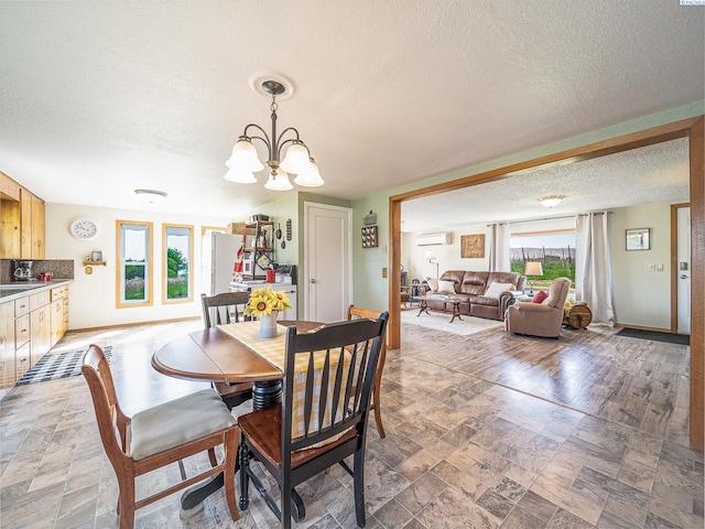 3680 E Euclid Rd, Mabton, WA 98935 - dining area featuring a textured ceiling, a wall mounted AC, a chandelier, light stone finish flooring, and baseboards