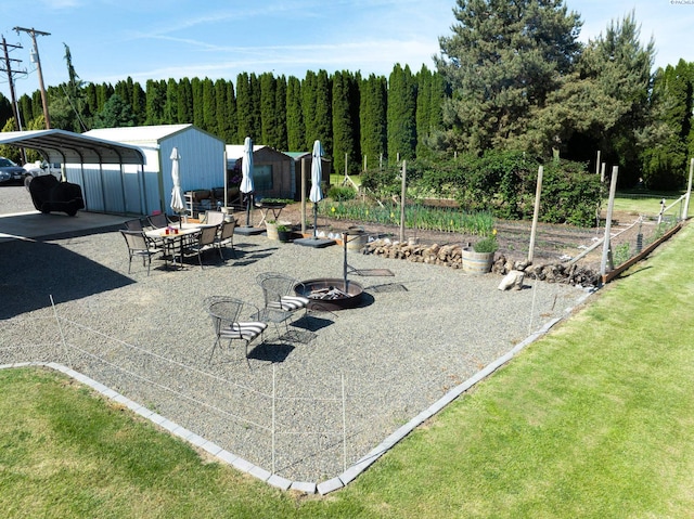 3680 E Euclid Rd, Mabton, WA 98935 - view of patio / terrace with a vegetable garden, a detached carport, an outdoor fire pit, and a view of trees
