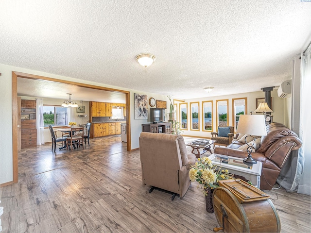 3680 E Euclid Rd, Mabton, WA 98935 - living area featuring a textured ceiling, a wall mounted AC, a chandelier, wood finished floors, and baseboards
