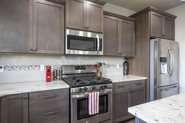3303 S Taft St, Kennewick, WA 99338 - kitchen featuring appliances with stainless steel finishes, backsplash, dark brown cabinetry, and light stone counters