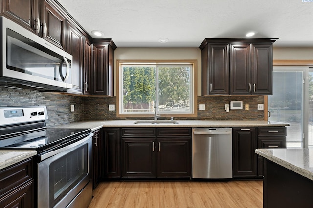 4505 S Dayton Ct, Kennewick, WA 99337 - kitchen with appliances with stainless steel finishes, light wood-style flooring, tasteful backsplash, light stone counters, and dark brown cabinets