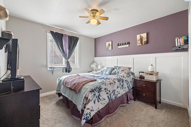 bedroom featuring a ceiling fan, a wainscoted wall, and carpet flooring