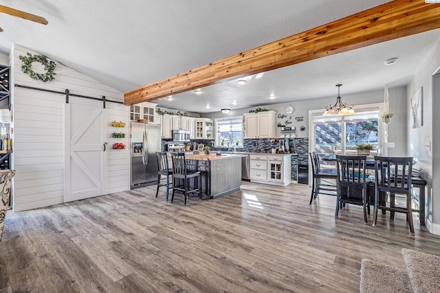 kitchen with a barn door, stainless steel appliances, wood finished floors, and a center island