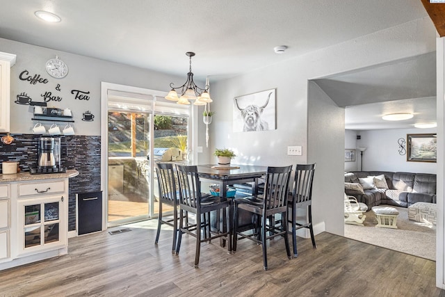 dining area with a notable chandelier, visible vents, and wood finished floors