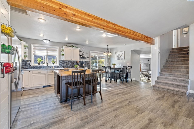 kitchen featuring open shelves, tasteful backsplash, beamed ceiling, and light wood-style flooring