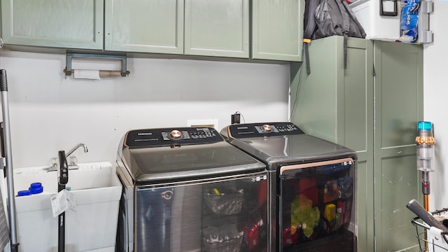 laundry room with sink, washing machine and dryer, and cabinets