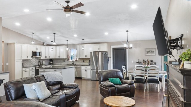 living room with dark wood-type flooring, lofted ceiling, sink, and ceiling fan with notable chandelier