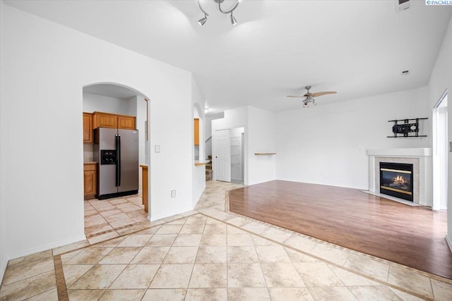 unfurnished living room featuring a high end fireplace, ceiling fan, and light tile patterned flooring