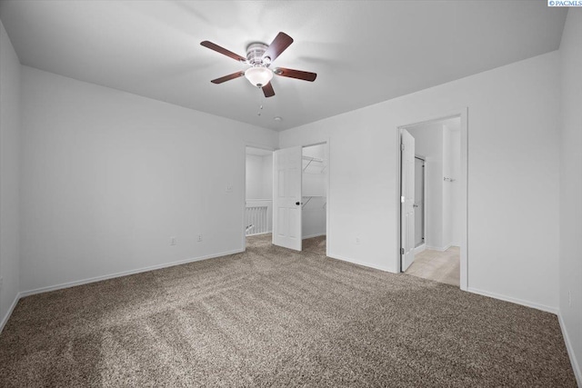 unfurnished bedroom with a spacious closet, ceiling fan, light carpet, ensuite bath, and a closet