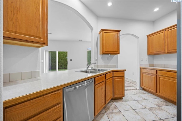 kitchen featuring dishwasher, sink, light tile patterned floors, and kitchen peninsula