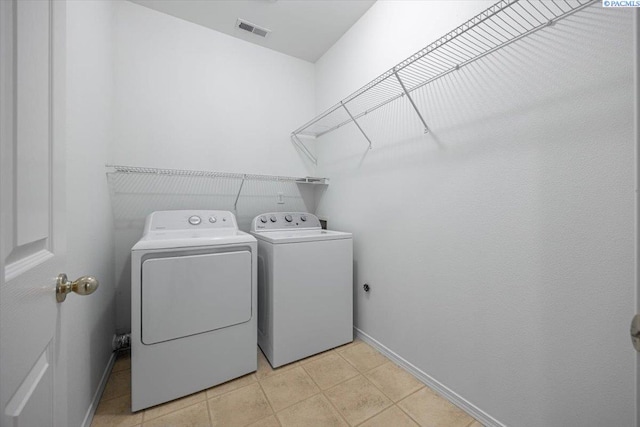 laundry area featuring washing machine and clothes dryer and light tile patterned floors