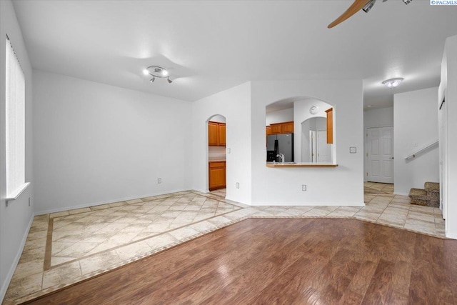 unfurnished living room with ceiling fan, sink, and light hardwood / wood-style floors