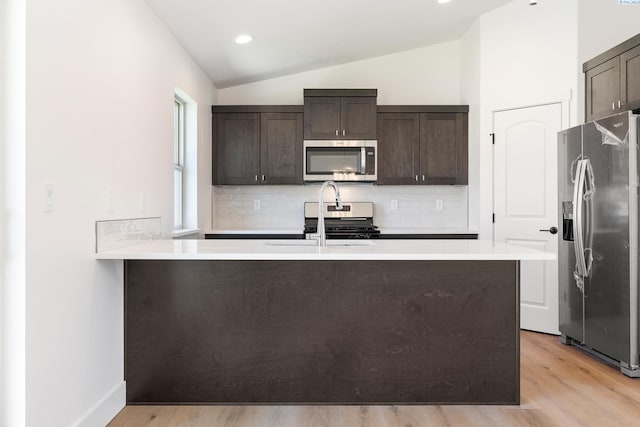 6562 W 30th Pl, Kennewick, WA 99338 - kitchen with appliances with stainless steel finishes, lofted ceiling, dark brown cabinetry, decorative backsplash, and a sink