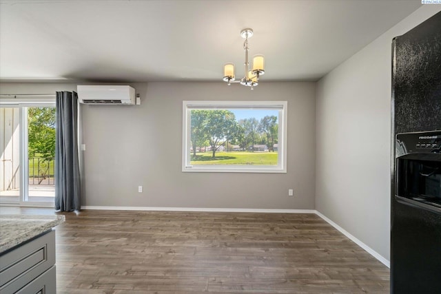 unfurnished dining area featuring a wall mounted air conditioner, a chandelier, wood finished floors, and baseboards