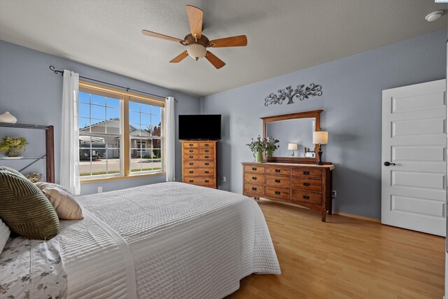 bedroom featuring baseboards, light wood-style flooring, and ceiling fan