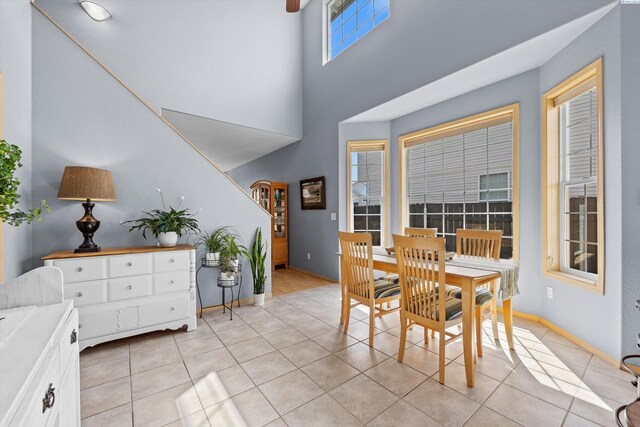 dining area with baseboards, light tile patterned floors, and a high ceiling