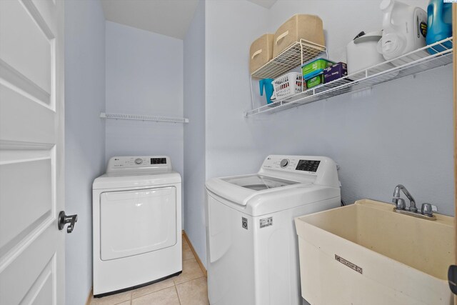 clothes washing area featuring a sink, laundry area, light tile patterned flooring, and independent washer and dryer