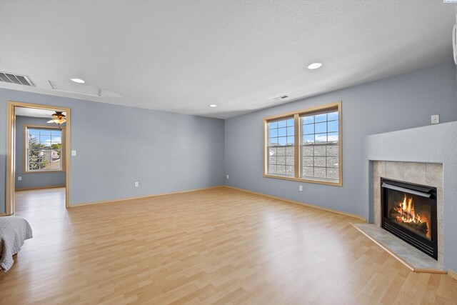 unfurnished living room with recessed lighting, visible vents, a tile fireplace, and light wood-style floors