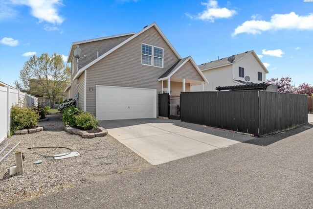 exterior space with an attached garage, a gate, fence, and concrete driveway