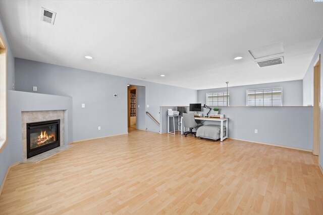 living room with recessed lighting, visible vents, a glass covered fireplace, and wood finished floors