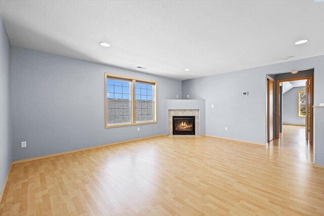 unfurnished living room with recessed lighting, baseboards, light wood-style flooring, and a fireplace