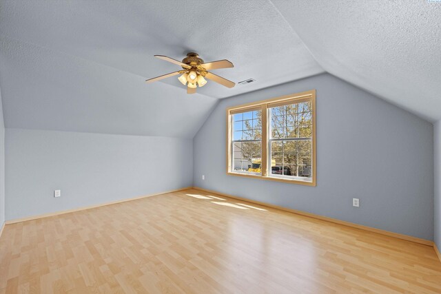 bonus room with a ceiling fan, a textured ceiling, visible vents, and wood finished floors