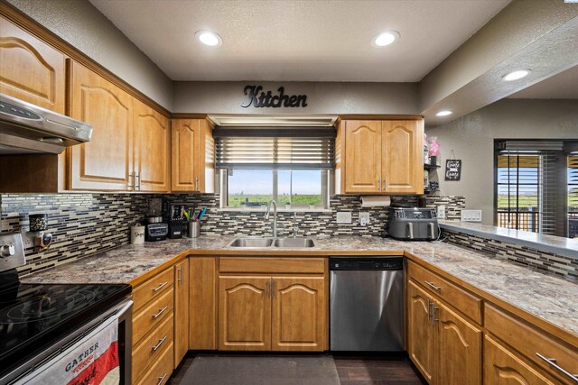 kitchen featuring a wealth of natural light, backsplash, appliances with stainless steel finishes, and a sink